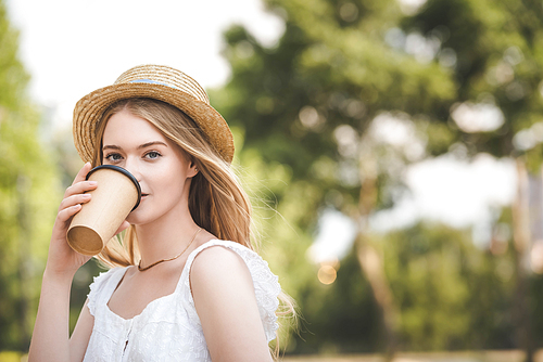 beautiful girl in white dress and straw hat holding paper coffee cup and 