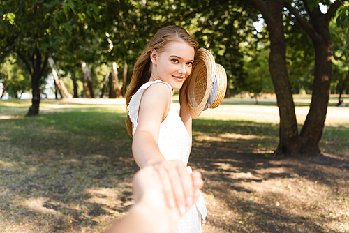 cropped view of man holding beautiful girl while young woman holding straw hat and 