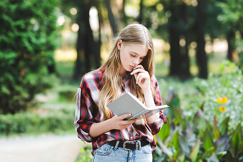 focused young girl in casual clothes reading book