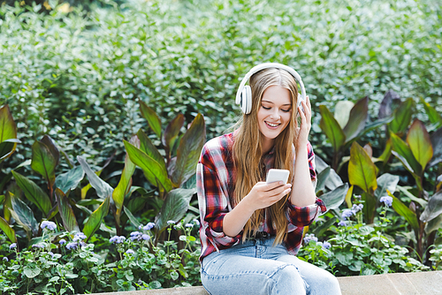 beautiful girl in casual clothes smiling while listening to musing on headphones