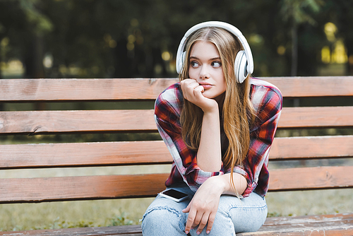 beautiful girl in casual clothes listening to musing on headphones and looking away