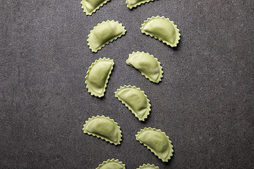 top view of raw green ravioli on grey textured surface