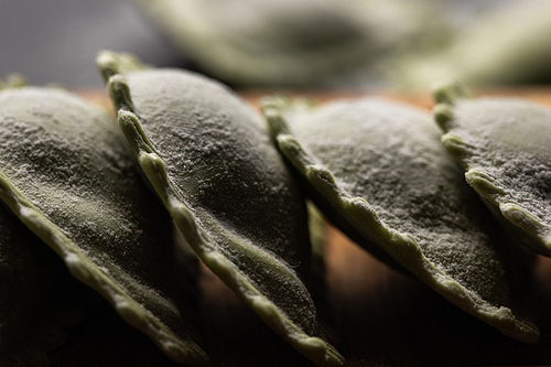 close up view of raw green ravioli in stack