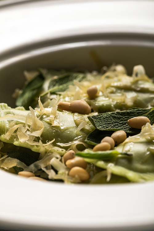 close up view of delicious ravioli with melted cheese, pine nuts and sage