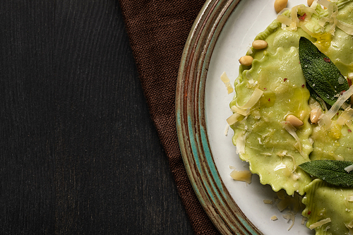 close up view of delicious green ravioli with sage, cheese and pine nuts served in vintage plate