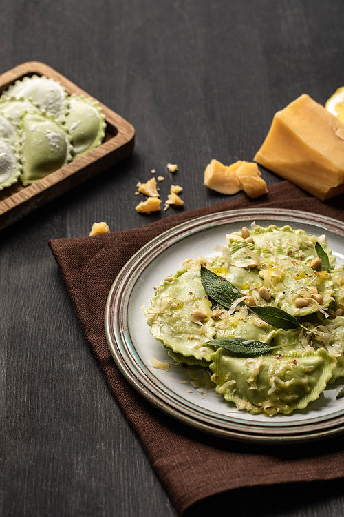 green ravioli with melted cheese, pine nuts and green sage leaves in retro plate near cheese