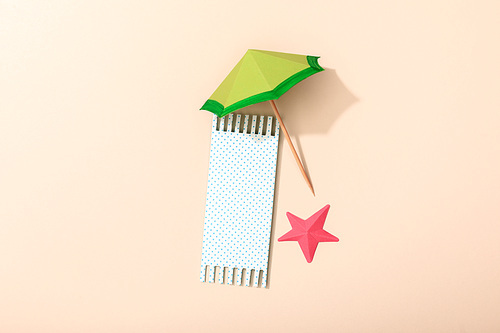 top view of paper beach with towel, umbrella and starfish