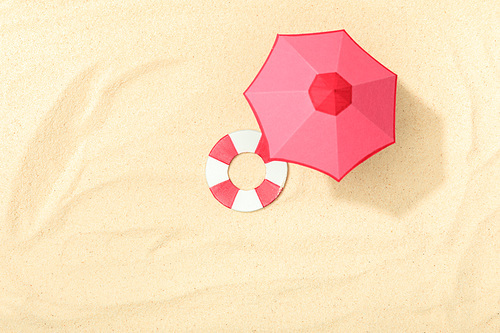 top view of paper beach with lifebuoy and pink umbrella on textured sand