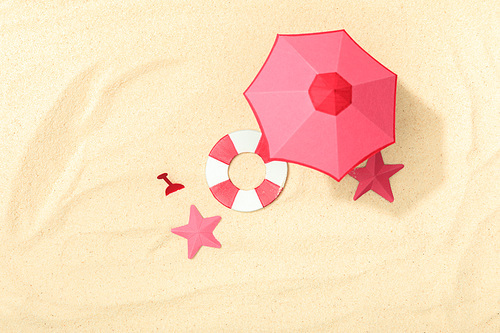 top view of paper beach with lifebuoy, pink umbrella and starfishes on textured sand