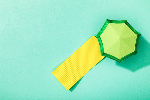 top view of paper towel and umbrella on turquoise background