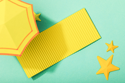 top view of paper cut yellow towel and umbrella near starfishes on turquoise background