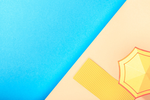 top view of paper blue sea with towel and umbrella on shore