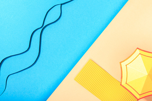 top view of wavy paper blue sea with towel and umbrella on shore