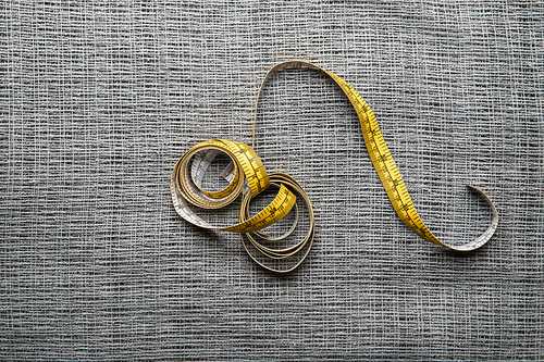 top view of yellow measuring tape on textured sackcloth background