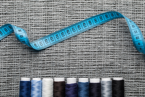 top view of blue and grey thread coils with measuring tape on sackcloth