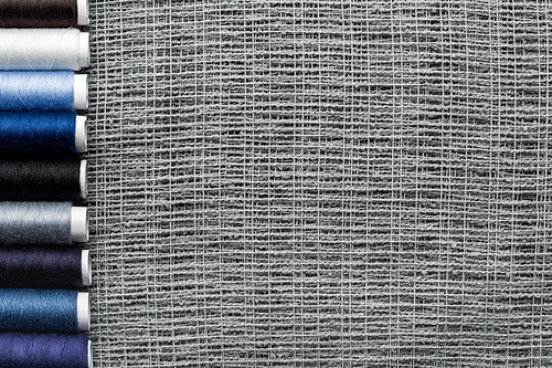 top view of blue and grey thread coils in row on sackcloth with copy space