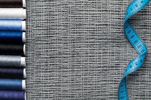 top view of blue and grey thread coils on sackcloth with measuring tape and copy space