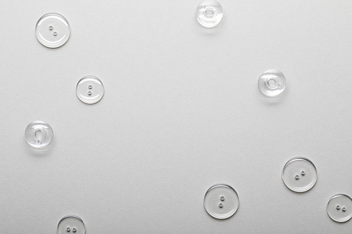 top view of transparent clothing buttons isolated on grey with copy space