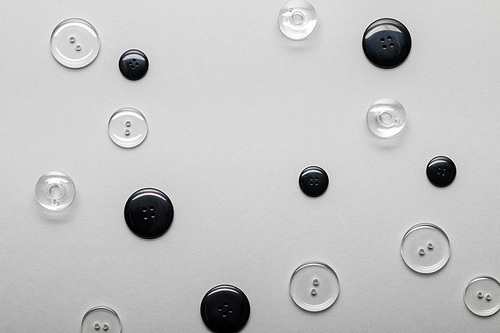 top view of transparent and black clothing buttons isolated on grey