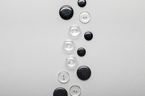 top view of arranged black and transparent clothing buttons isolated on grey with copy space