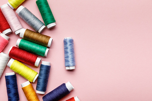top view of scattered colorful thread coils isolated on pink with copy space