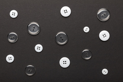 top view of monochrome clothing buttons isolated on black