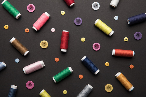 top view of colorful thread coils with various buttons isolated on black