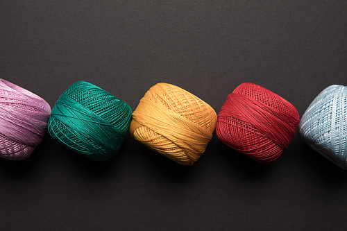 top view of arranged colorful balls of knitting yarn isolated on black
