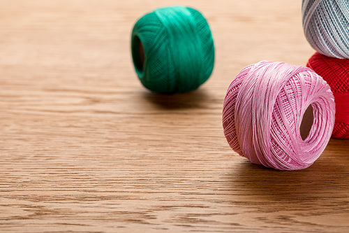 colorful cotton knitting yarn balls on wooden table with copy space