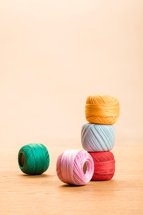 colorful cotton knitting yarn balls on wooden table isolated on beige with copy space
