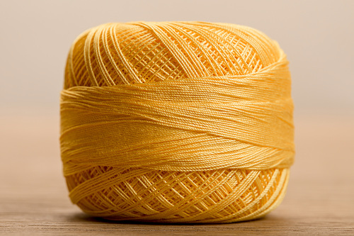 close up view of yellow cotton knitting yarn ball on beige