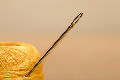 selective focus of yellow cotton knitting yarn ball on beige with copy space