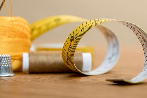 selective focus of measuring tape with thread coil on wooden table