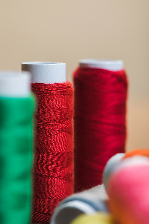 selective focus of red cotton thread coils isolated on beige