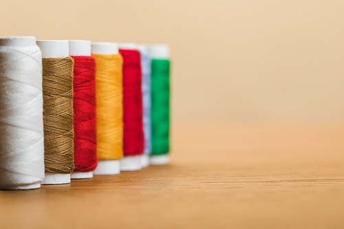 colorful cotton thread coils in row isolated on beige with copy space