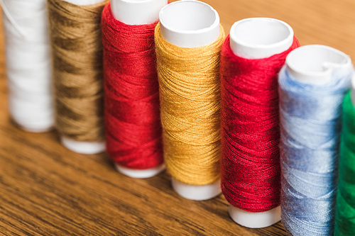 colorful cotton thread coils in row on wooden surface