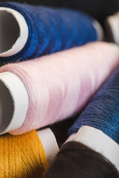 close up view of pink, blue and yellow cotton thread coils