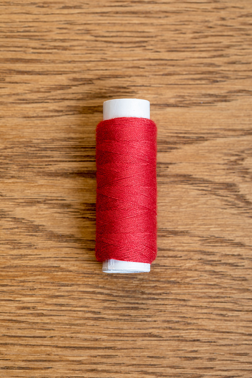 top view of red cotton thread coil on wooden surface