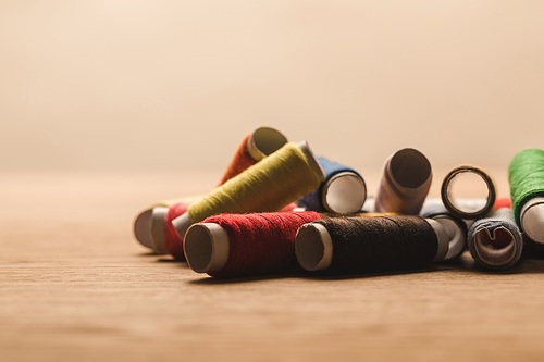 selective focus of colorful cotton thread coils on table isolated on beige