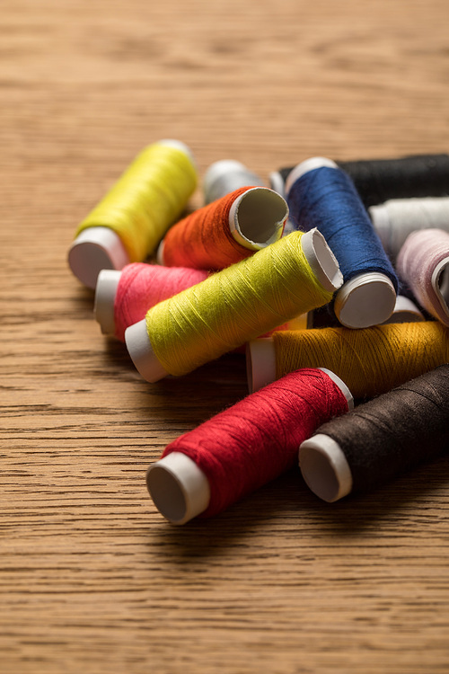 scattered colorful cotton thread coils on wooden surface