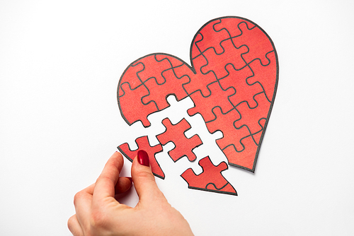 cropped view of woman touching drawn red heart shape jigsaw isolated on white