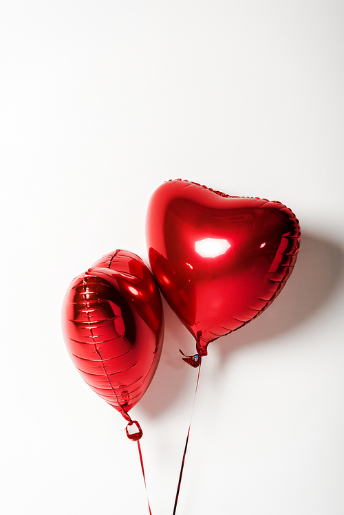 red and shiny heart shaped balloons on white with copy space