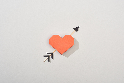 Top view of decorative paper heart with arrow on grey background