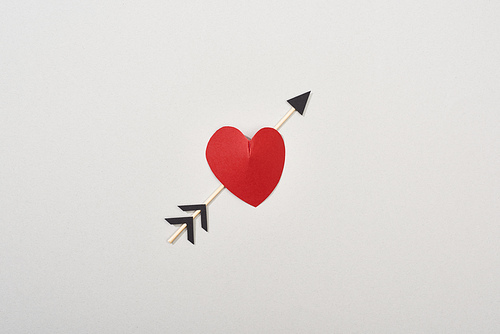 Top view of red paper in heart shape with arrow isolated on grey