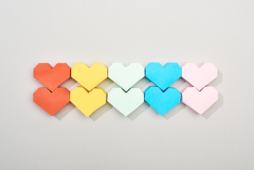 Top view of colorful paper hearts on grey background