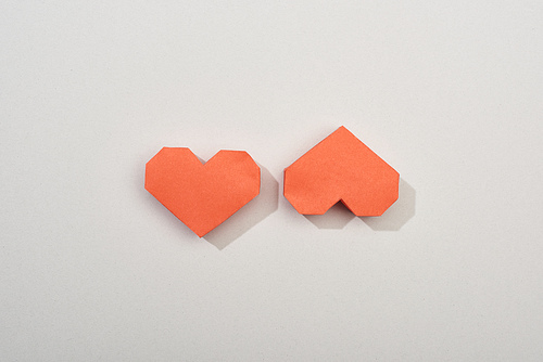 Top view of two red paper hearts on grey background