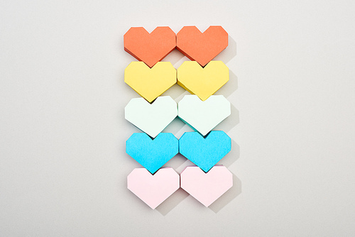 Top view of colorful heart shaped papers on grey background