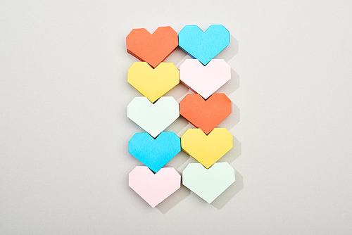 Top view of colored heart shaped papers on grey background