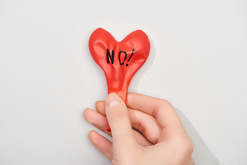 Top view of woman holding red balloon with no lettering on grey background, cropped view