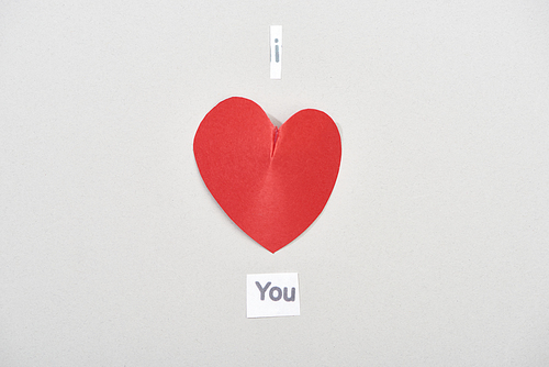 Top view of i love you lettering with paper heart on grey background